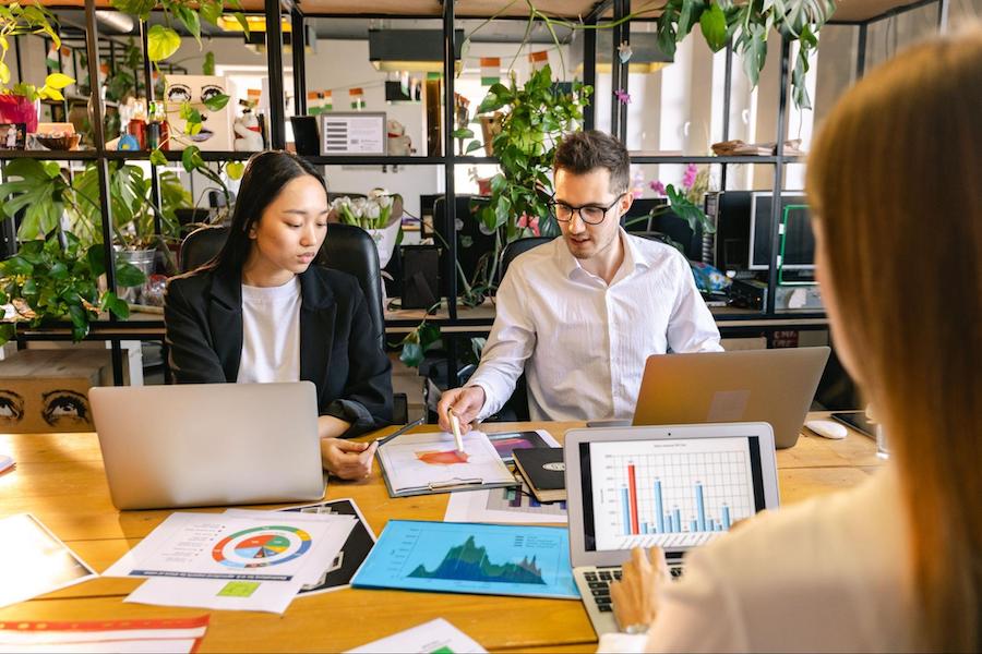 man and woman sitting at a table look at a spreadsheet project scope - line items